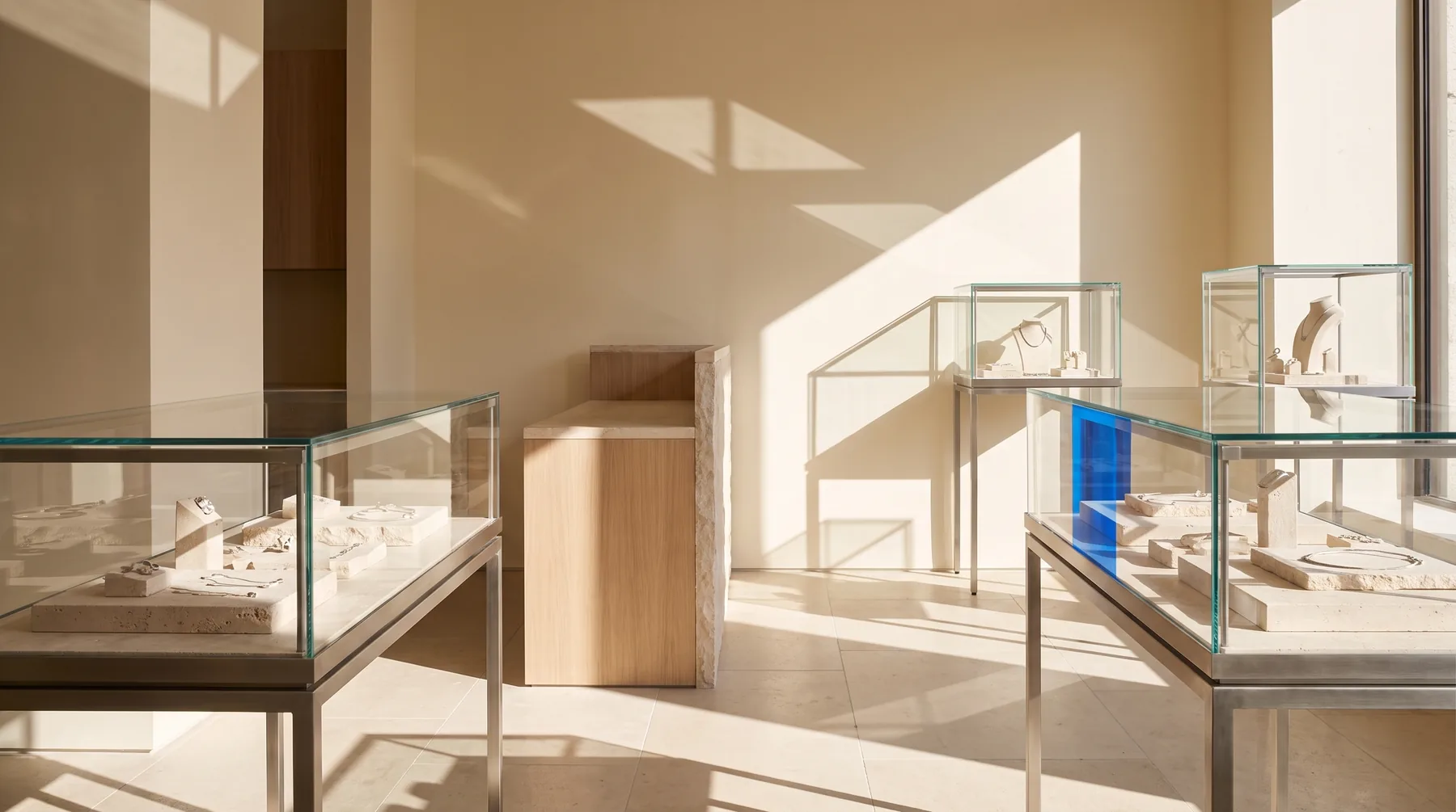 The interior of a contemporary independent jewellery store, with simple glass display cases on pale stone risers in daylight.